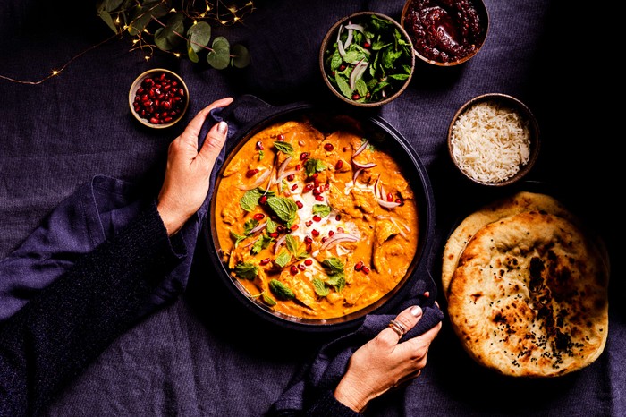 Butter turkey curry Someone setting a pan of butter turkey curry onto a set table