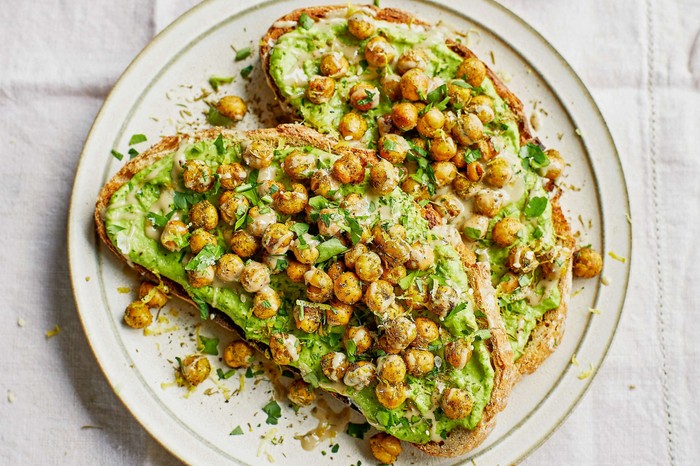 Crispy chickpeas on green toast Two slices of chickpeas on toast on a white plate