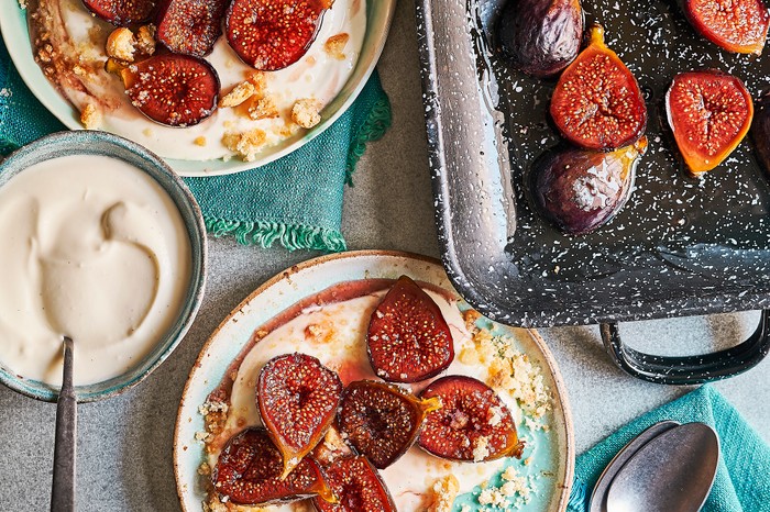 Baked figs with amaretto White plates topped with mascarpone and halves purple figs