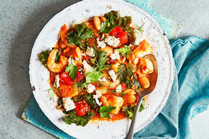 Quick fish stew One-pan Fish Stew in a White Bowl on a Blue Wooden Board