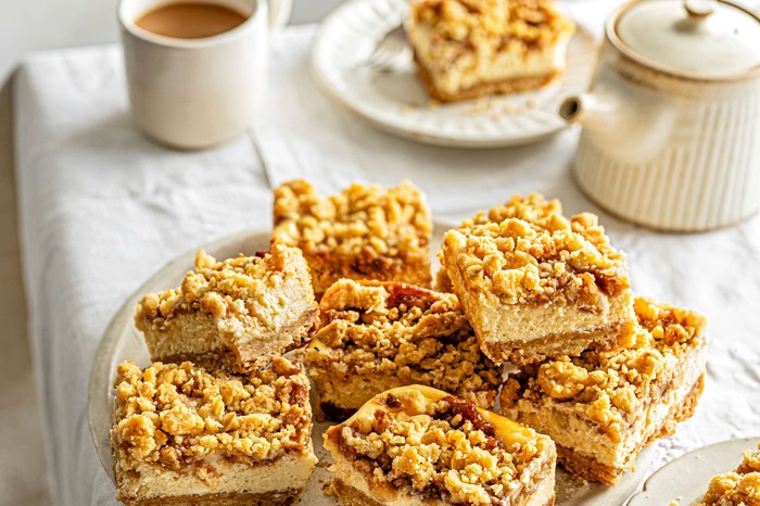 Caramelised apple and brown butter cheesecake bars A plate of apple cheesecake bars with tea in the background