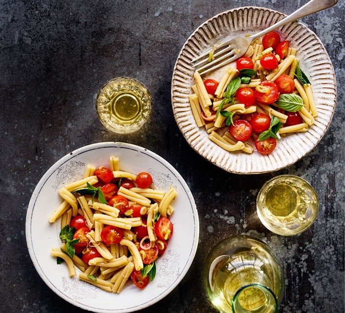 Casarecce Tomato Pasta Two bowls of tomato pasta with glasses of white wine