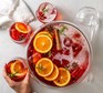 A bowl of Aperol punch with orange slices and cinnamon sticks floating on top