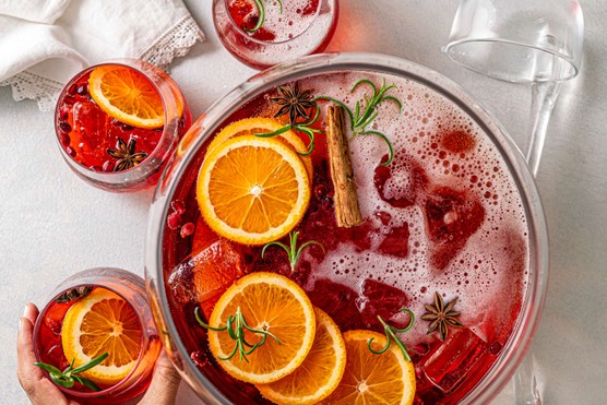 A bowl of Aperol punch with orange slices and cinnamon sticks floating on top