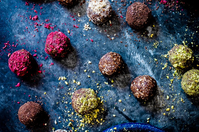 Coconut butter, date and cranberry energy balls Coconut butter, date and cranberry energy balls with two plates of pistachios and dried cranberries on the side