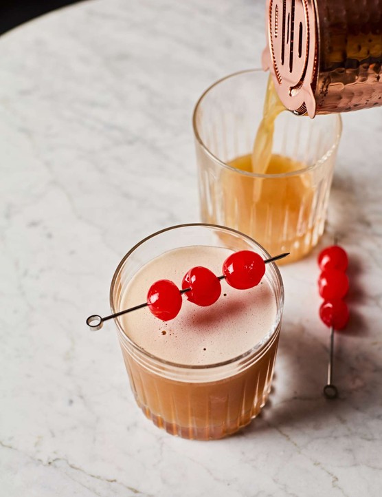A whisky sour cocktails with cherries on top