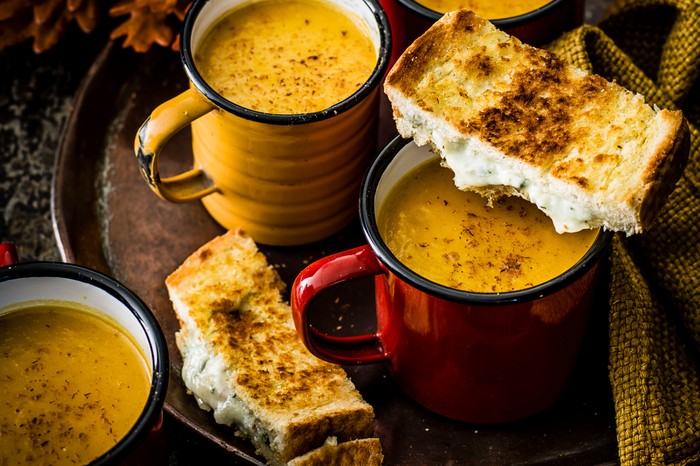 Pumpkin soup Two mugs full of pumpkin soup, next to two slices of a blue cheese toastie