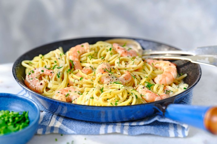 A deep frying pan with prawn pasta in it