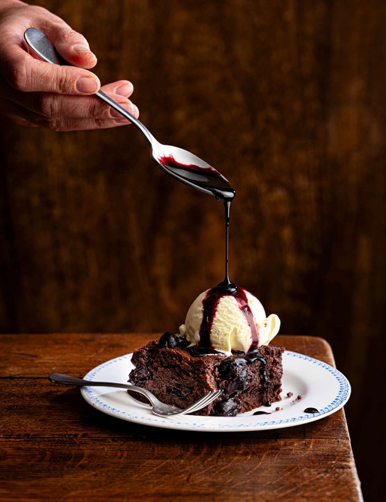 A single chocolate brownie with ice cream and chocolate sauce on top