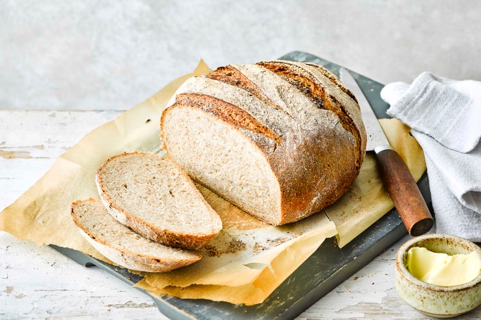 Dark Rye Bread loaf sliced with knife and butter