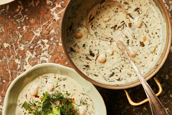 Dovga Azeri (warm yogurt soup) Two bowls of white soup decorated with herbs