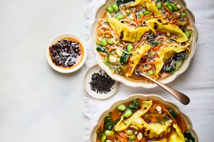 Fragrant dumpling and noodle broth Two bowls of broth with dipping sauces on the side