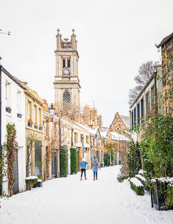 Four festive UK city getaways for shopping, eating and exploring A view along a curving traditional mews street in Edinburgh's Stockbridge following heavy snow.