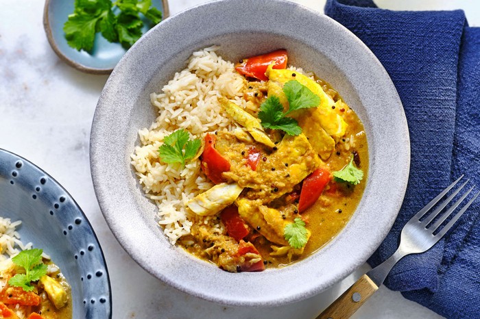 A fish curry with rice in a white serving bowl