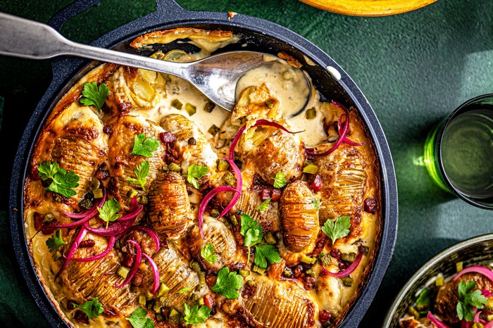 Hasselback tartiflette with pickle salad A hasselback tartiflette with pickle salad, with a spoon in it