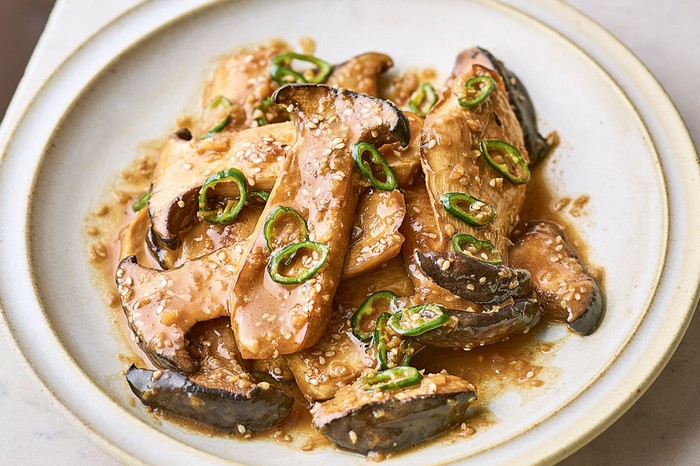 Korean king oyster mushrooms (seasongi beoseot bokkeum) Plate with pile of mushrooms and buttery sauce topped with chillies