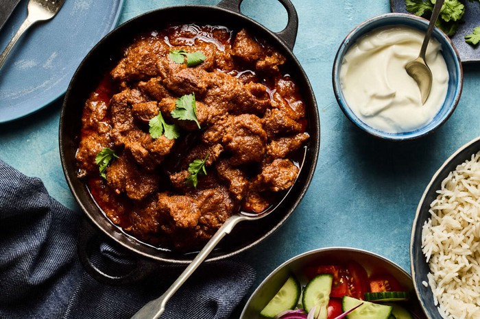 Slow-cooked mutton curry A mutton curry with rice and dips on the side