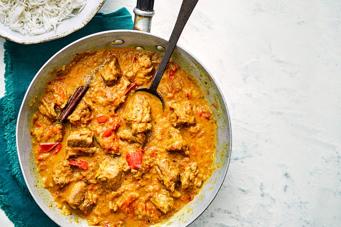 Easy Lamb Bhuna Recipe Pan of lamb bhuna next to a bowl of rice