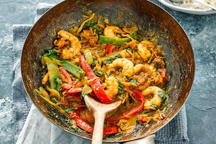 Prawn Stir Fry Recipe A silver wok is filled with prawns, chopped peppers and green vegetables