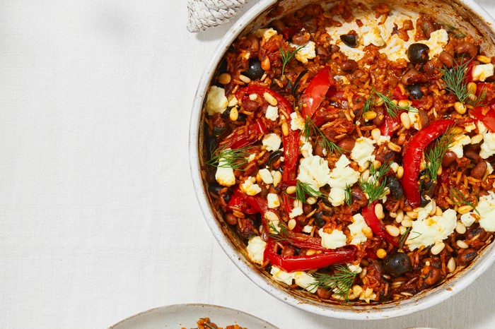 Greek-style baked rice A casserole dish filled with tomato rice, red peppers and topped with pine nuts and feta
