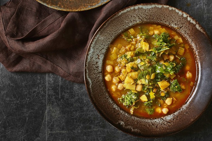 Green Lentil Soup Recipe With Harissa Two black bowls filled with green lentils and chickpeas in a broth