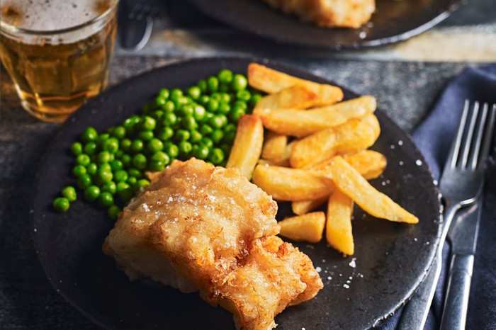 Fish and chips Beer battered cod, chips and peas on a plate dinner plate