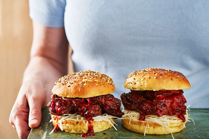 Korean BBQ chicken burger Someone holding a board with two chicken burgers on it