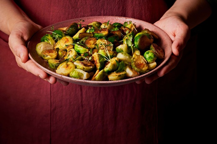 Marmalade-glazed sprouts with chestnuts A dish of sprouts in somebody's hands