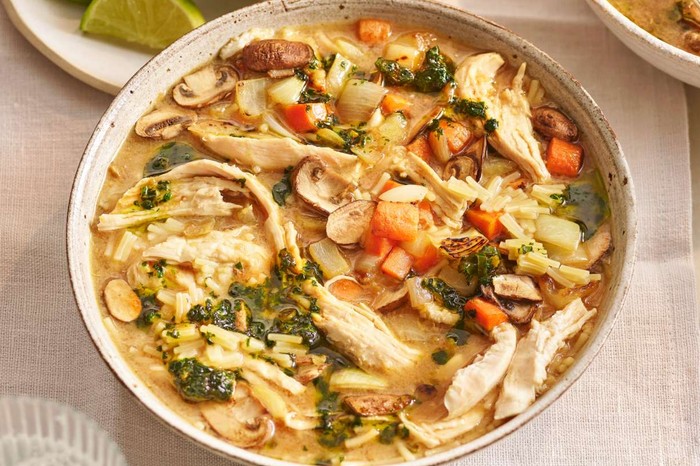 Umami chicken soup with coriander chilli oil Two bowls of chicken soup on a set table