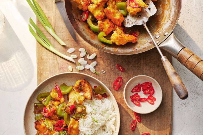 Gobi Manchurian Gobi Manchurian in a wok with a full plate and spring onions on the side