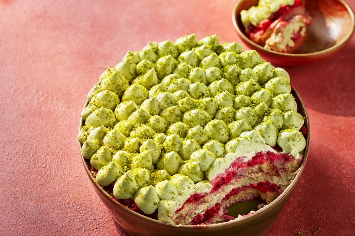 Pistachio and raspberry tiramisu A whole pistachio and raspberry tiramisu with a slice taken out of it