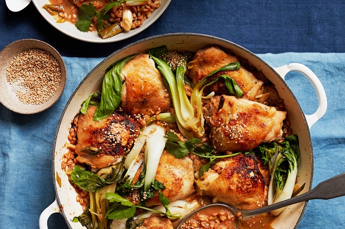 Healthy one-pot chicken A white casserole dish filled with crispy chicken thighs and green pak choi