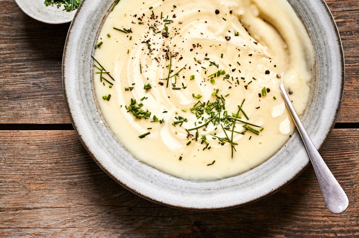 Parsnip and apple soup A grey bowl filled with creamy parsnip soup and topped with chopped chives