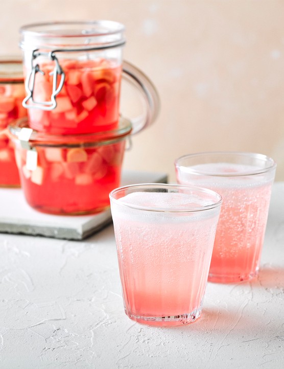 Rhubarb gin and tonic in a glass with a jar of rhubarb behind