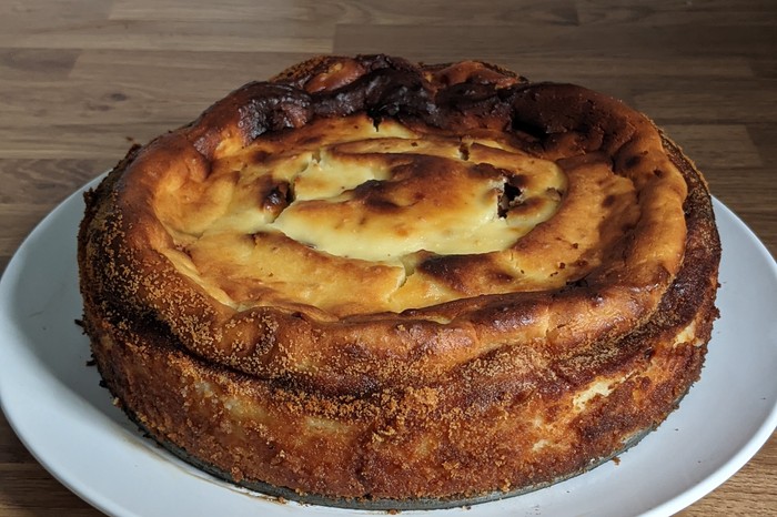 Ricotta cake A golden ricotta cake on a white plate, sat on a wooden worktop