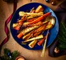 Roasted parsnips and carrots A blue serving bowl with roasted root veg on it