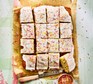 School cake A school cake topped with icing and sprinkles cut into squares on a sheet of brown baking parchment