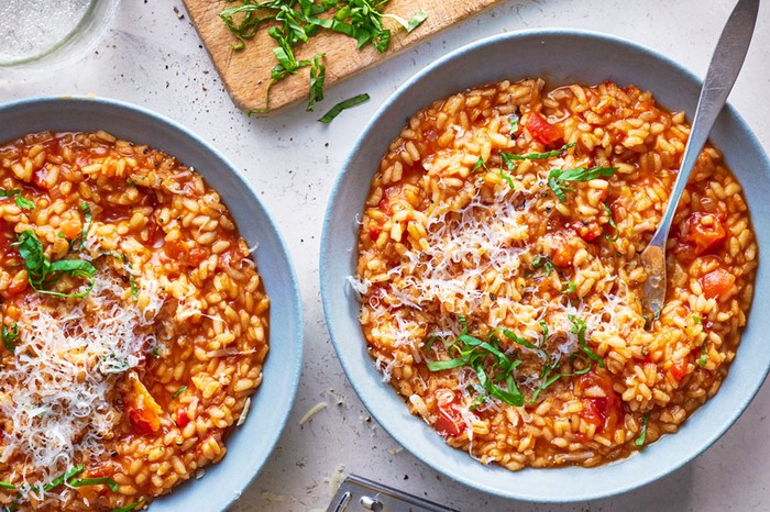 Tomato risotto Two bowls of tomato risotto next to a chopping board with basil on top