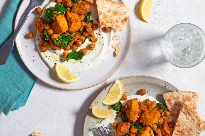 Tumeric Chicken and Chickpeas Two plates of spiced chicken with lemon wedges on the side