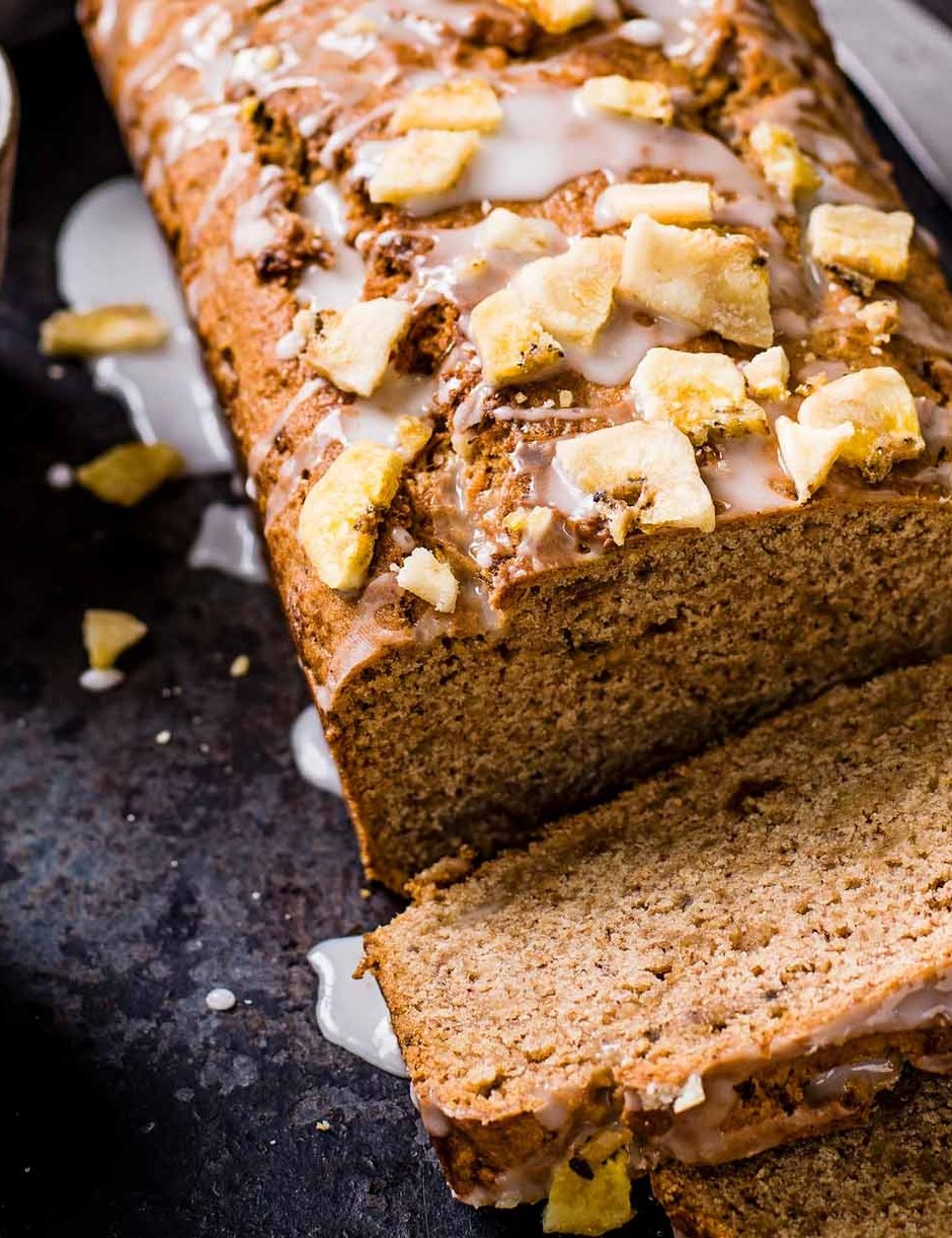 vegan banana loaf on a dark background with two cups of tea