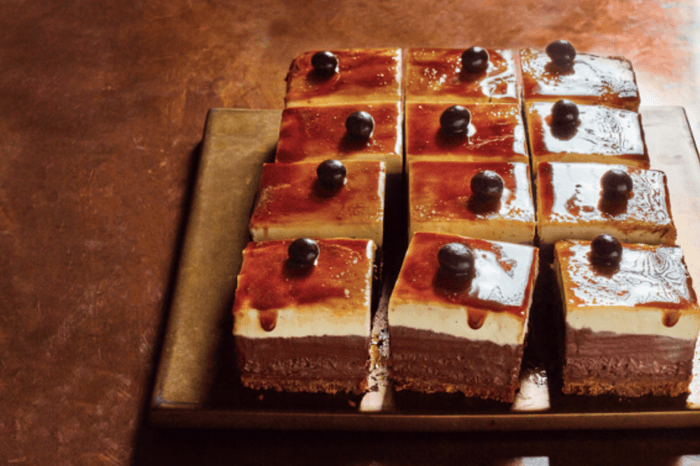 Espresso martini cheesecake Brown-glazed cheesecake cut into squares sat on a wooden board with a brown marbled background